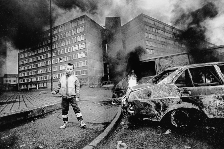 Boy and flaming car outside Divis flats.